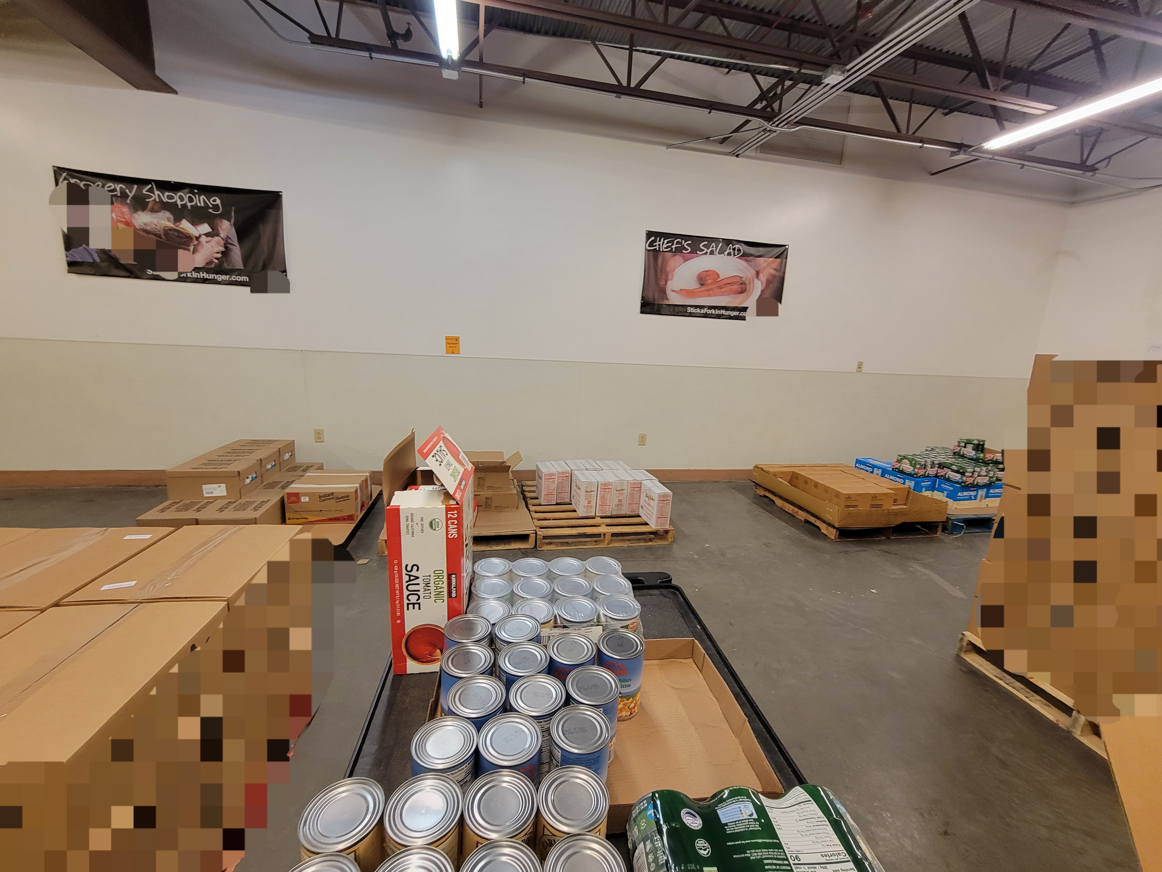 Shelf cart with food on top with pallets of boxes to the left and right of it.